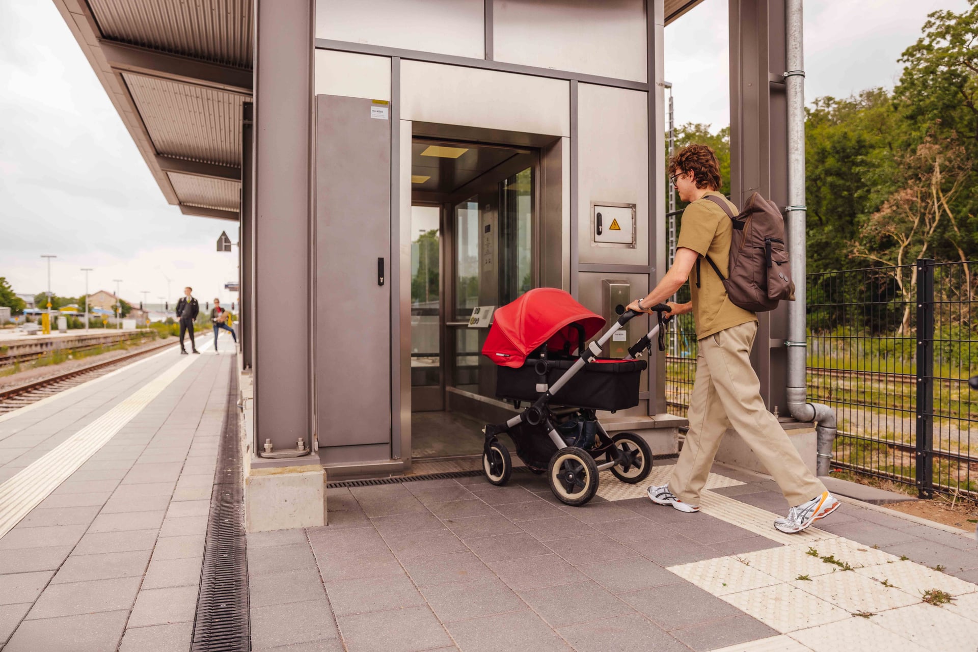 Mann mit Kinderwagen nutzt den Aufzug am Bahnsteig
