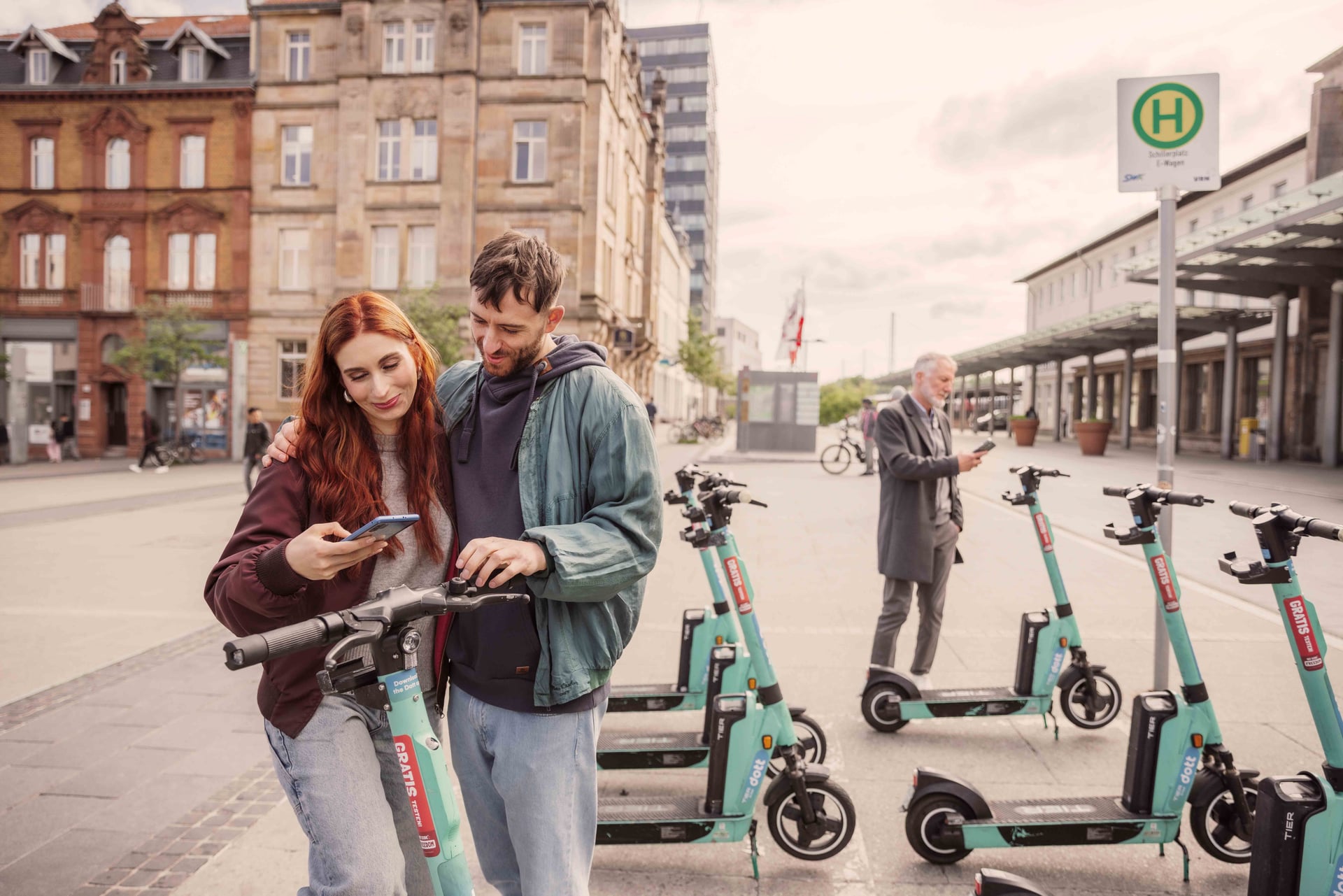 Ein Pärchen entsperrt einen E-Scooter am Bahnhof