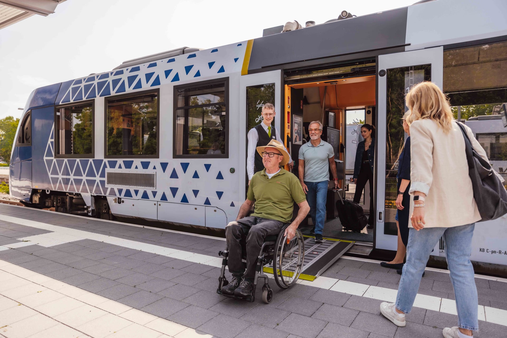 Mann im Rollstuhl verlässt über die Rampe den Zug