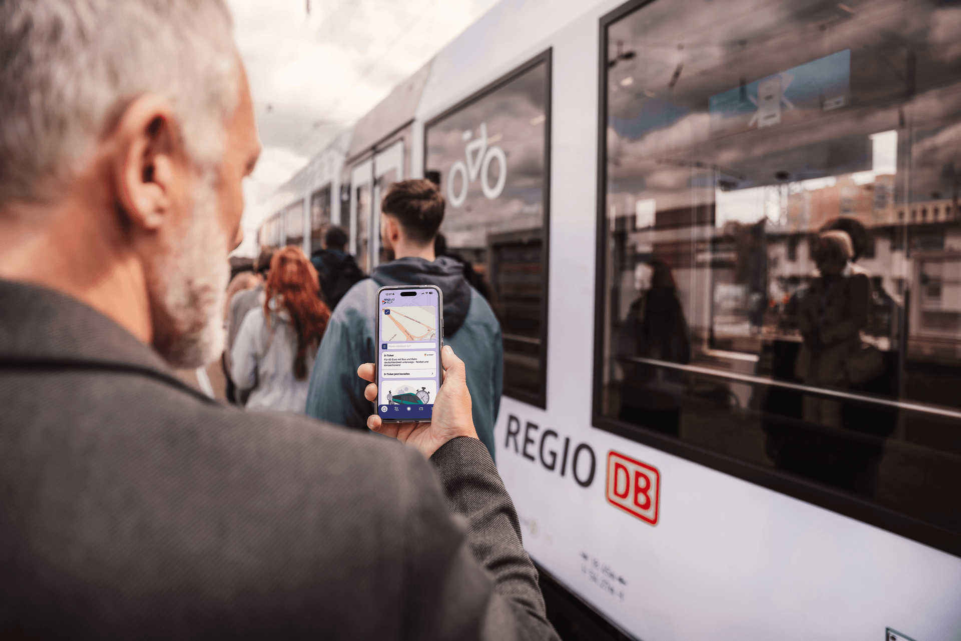 Mann steht vor einem Zug mit seinem Handy in der Hand