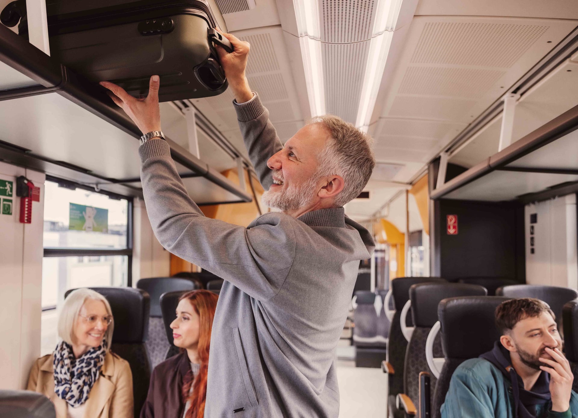 Mann hebt seinen Koffer in die Gepäckablage