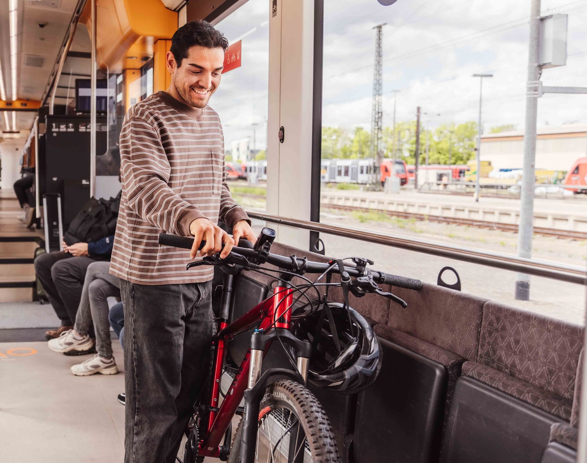 Mann mit seinem Fahrrad im Fahrrad-Abteil eines Zuges
